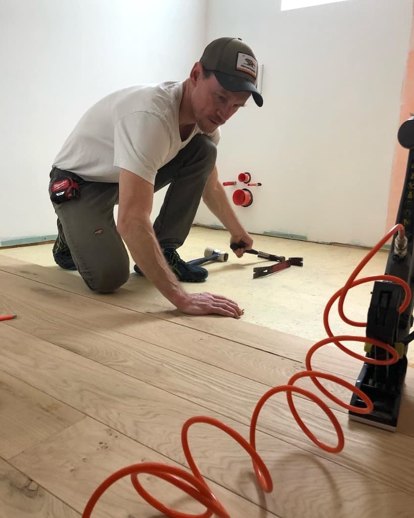 Craftsman operating floor-sanding machine during restoration