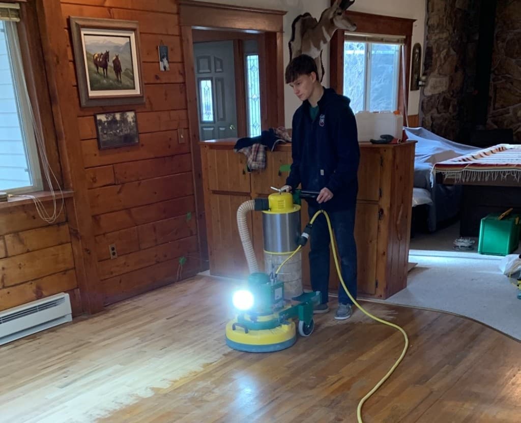 Craftsman installing hardwood flooring with hand tools