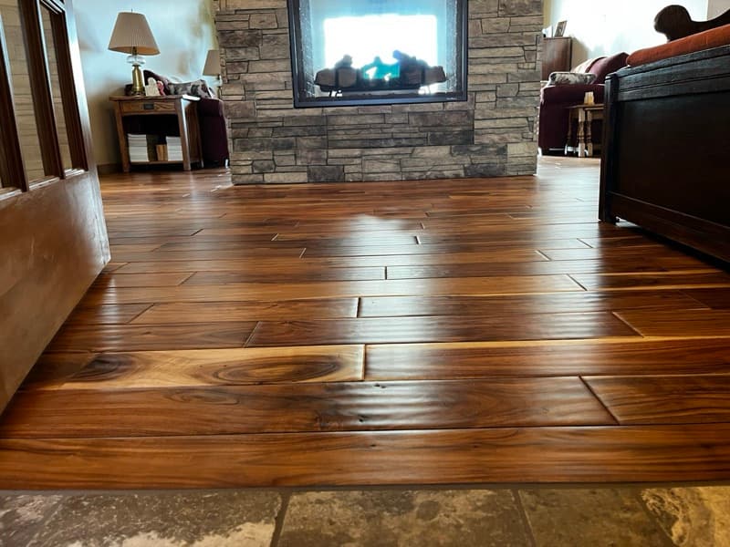 A beautifully restored living room in Cody, Wyoming, with bright August sunlight streaming through large windows onto a pristine, evenly toned hardwood floor