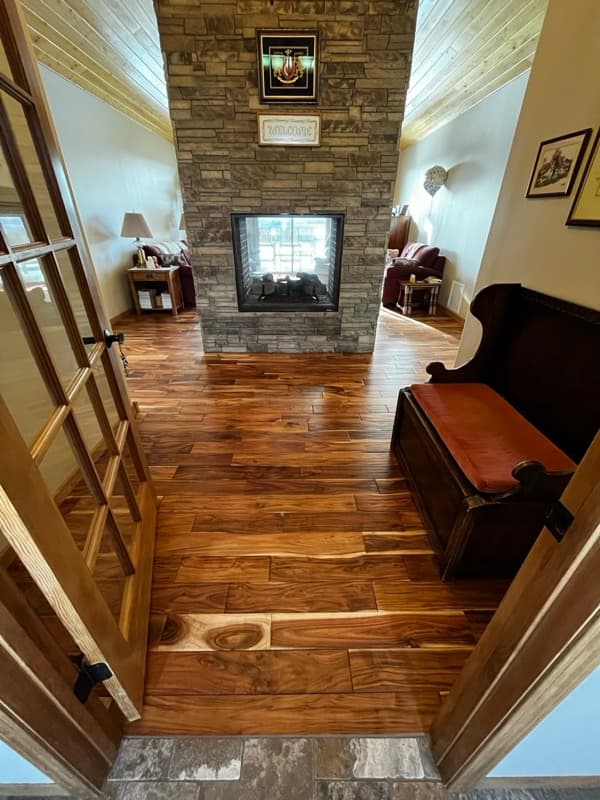 Sunlit hardwood floors beside a stone fireplace in a Wyoming home